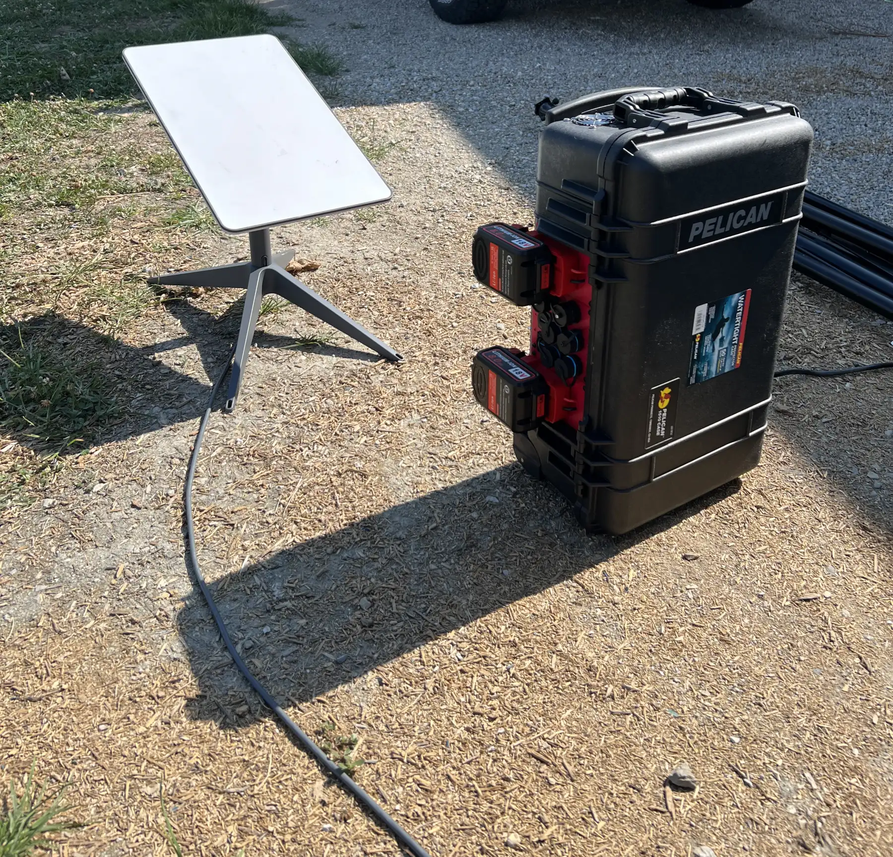 ShowDropGo field kit: a Pelican case with battery packs beside a satellite dish, set up outdoors